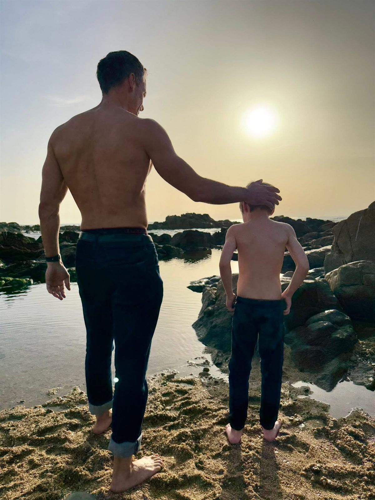 Taylor and his son looking out over rocky tide pools at sunset.